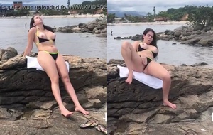 Morena sensual exibindo o corpo pelado na praia enquanto faz uma siririca provocante